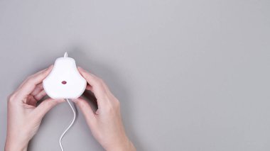 Parlak gri bir arkaplan üzerinde beyaz monitör kalibrasyon aracını kavrayan eller, dijital görüntülerde renk doğruluğunun önemini vurgular