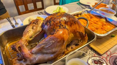 Kızarmış hindi, canlı garnitürlerle çevrili güzel bir yemek masasının orta süsüdür. Şükran Günü aile yemeği havasını uyandırır.