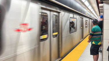 Toronto, Canada - June 29, 2025: Subway TTC train approaches the station as passengers stand on the platform, highlighting the hustle of urban transportation and daily commuting experiences
