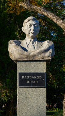 Bişkek, Kırgızistan - 01 Ekim 2024: Razzakov Iskhak anıtı, yemyeşil ve sonbahar yapraklarıyla süslenmiş, Kırgız tarihini temsil eden bir parkta gururla duruyor