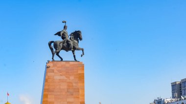 Bişkek, Kırgızistan - 01 Ekim 2024: Kırgız kültürünün bir sembolü olan Manas Heykeli, canlı mavi bir arkaplan ile Bişkek 'te görkemli bir şekilde duruyor