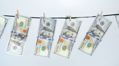Yüz dolarlık banknotlar çamaşır ipinde kuruyor, para aklamayı ve finansal suçu sembolize ediyor. Yasadışı yollardan elde edilen paranın kaynağını gizleme ve temiz parayı temsil ediyor..