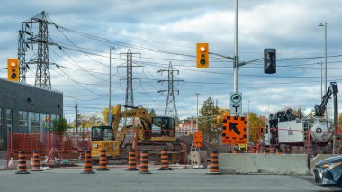 Ottawa ON, Kanada - 25 Ekim 2025: Kazı makinesi ve yol tabelalarıyla dolu bir inşaat alanı, kentsel gelişim ve altyapı çalışmaları sergileniyor