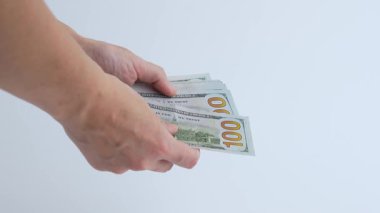 Eller, enflasyonun para üzerindeki etkilerini gösteren birkaç yüz dolarlık banknotlar sayıyor ve para biriminin detaylarına ve dokusuna odaklanıyor.