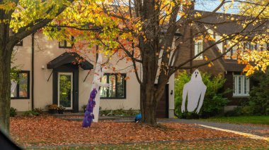 Ottawa On, Kanada - 25 Ekim 2025: Hayalet ve cadı figürlerinin yer aldığı cadılar bayramı süslemeleri banliyö evini sonbahar yapraklarıyla zenginleştiriyor, şenlikli ve davetkar bir ortam yaratıyor