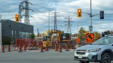 Ottawa ON, Kanada - 25 Ekim 2025: Yoğun inşaat sahasında ağır makineler, trafik işaretleri ve güvenlik konileri, kentsel gelişim ve dinamik bir şehir manzarasında yol çalışmaları yer alıyor