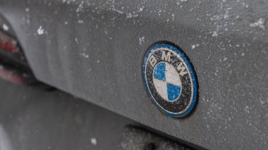 Gatineau QC, Kanada - 30 Kasım 2025: Bir arabanın arka tarafındaki BMW amblemi kar tarafından kısmen gizlenerek, kış havasının otomobiller üzerindeki etkilerini vurguluyor