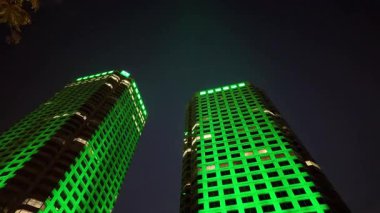 Montreal QC, Kanada - 24 Temmuz 2025: Gökdelenler yeşil ışıkta parlıyor, mimari özelliklerini vurguluyor ve geceleri büyüleyici bir şehir manzarası yaratıyorlar