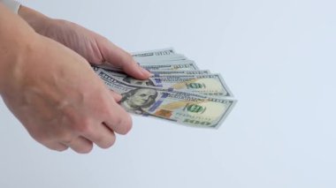 Eller ustalıkla 100 dolarlık banknotları sayıyor, para ile dokunsal etkileşimi vurguluyor, kamera ayrıntıları yakalamak için yakınlaşıyor.