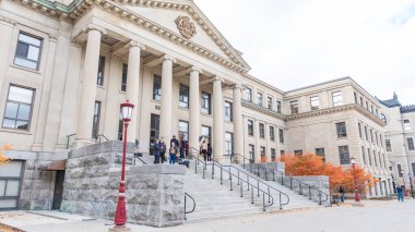Ottawa ON, Kanada - 25 Ekim 2025: uOttawa Üniversitesi 'nde renkli sonbahar yaprakları ve canlı bir kampüs ortamı ile çevrili basamaklarda yürüyen öğrenciler sütunlu görkemli bir bina bulunmaktadır.