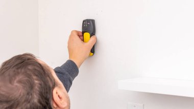 Siyah raf desteğinin yanındaki beyaz duvara vida takmak için sarı kablosuz matkap kullanan insanlar. Ev geliştirme, ek güvenlik, DIY takviyesi, elektrikli alet çalışması