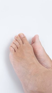 Pürüzsüz beyaz bir yüzeyde çıplak ayakla iki ayak yakın çekim yapmak, cilt detaylarını ve rahat duruşu vurgulamak, sakin ve huzurlu bir atmosfer yaratmak.