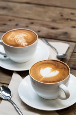 Tahta masada bir fincan sıcak latte sanat kahvesi.