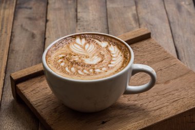 Tahta masada bir fincan sıcak latte sanat kahvesi.