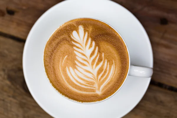 Κούπα ζεστό καφέ latte art σε ξύλινο τραπέζι — Φωτογραφία Αρχείου