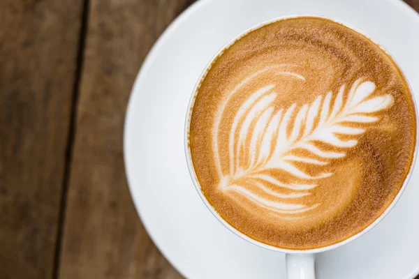 Tahta masada bir fincan sıcak latte sanat kahvesi.