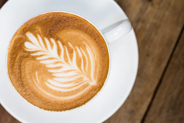 Filiżanka gorącej kawy sztuki latte na drewnianym stole — Zdjęcie stockowe