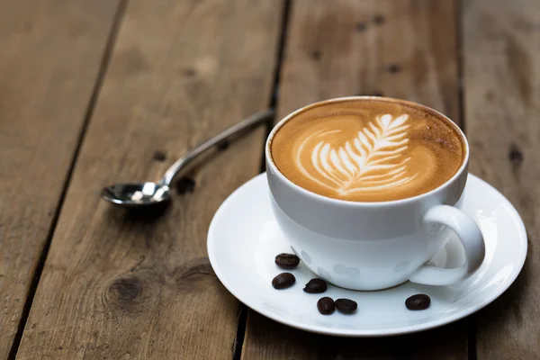 Tahta masada bir fincan sıcak latte sanat kahvesi.