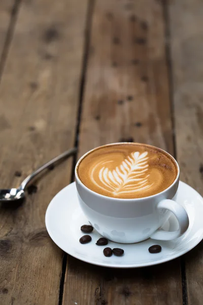 Tahta masada bir fincan sıcak latte sanat kahvesi.