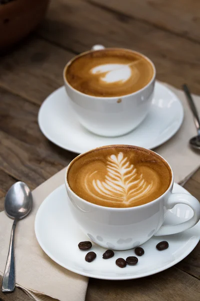 Tahta masada bir fincan sıcak latte sanat kahvesi.
