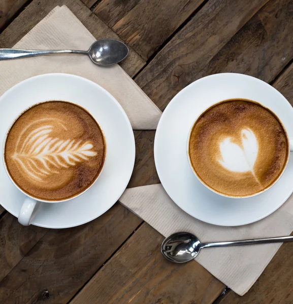 Tahta masada bir fincan sıcak latte sanat kahvesi.