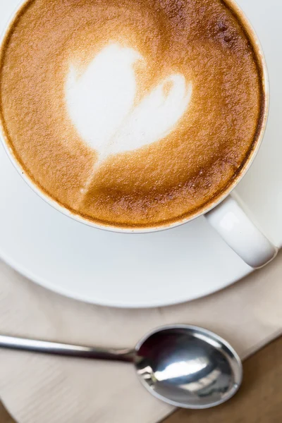 Tahta masada bir fincan sıcak latte sanat kahvesi.