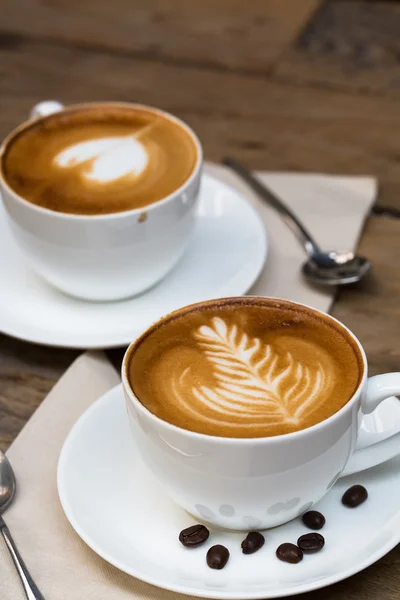 Tasse heißen Latte-Art-Kaffee auf Holztisch Stockbild