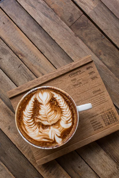 Xícara de café de arte quente latte na mesa de madeira — Fotografia de Stock