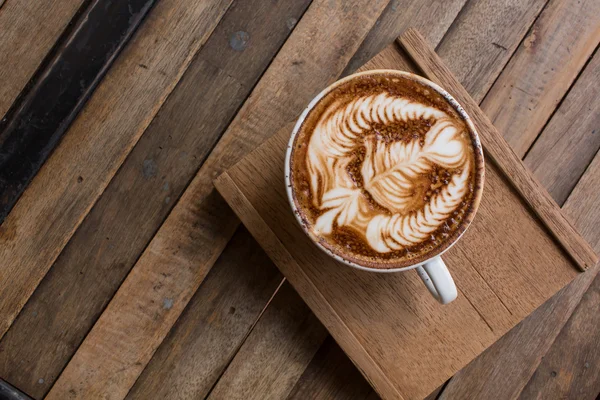 Tahta masada bir fincan sıcak latte sanat kahvesi.