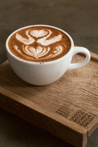 Tahta masada bir fincan sıcak latte sanat kahvesi.