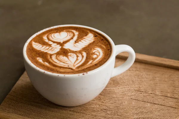 Κούπα ζεστό καφέ latte art σε ξύλινο τραπέζι — Φωτογραφία Αρχείου