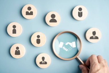 Şirket stratejisinde el sıkışma, işbirliği, insan kaynakları, liderlik, birlik ve iş ortaklığına odaklanan büyüteç.