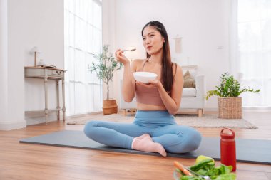 Sağlıklı meyve kasesi, granola, muz, böğürtlen ve yoğurt. Aktif giyimde bir kadın tarafından tutulmuş. Fitness beslenme, sağlık alışkanlıkları, temiz yemek ve sağlıklı bir sabah yaşam tarzı..