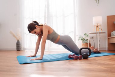 Antrenmandan sonra yatak odasında yoga minderinde uzanan bir kadın çocuk pozu veriyor. Sağlıklı yaşam tarzı, vücut iyileştirme, farkındalık ve evde esneklik eğitimi.