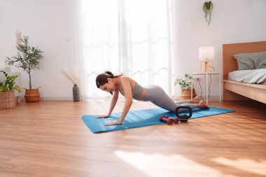 Antrenmandan sonra yatak odasında yoga minderinde uzanan bir kadın çocuk pozu veriyor. Sağlıklı yaşam tarzı, vücut iyileştirme, farkındalık ve evde esneklik eğitimi.