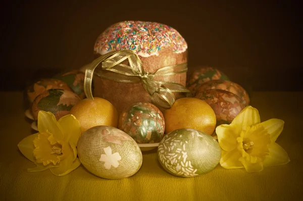 Jonquilles, gâteau de Pâques et œufs peints sur un fond sombre — Photo