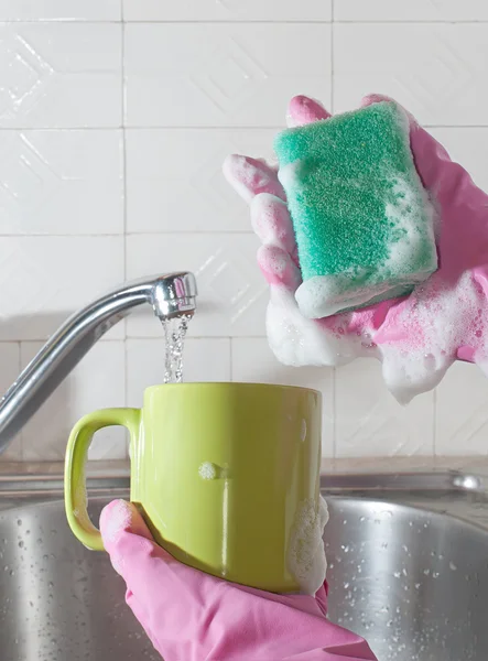 Les mains des femmes lavent la tasse dans l'évier de la cuisine avec une éponge savonneuse — Photo