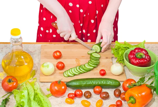 Женщина в фартуке срезала свежие овощи на кухонном столе — стоковое фото