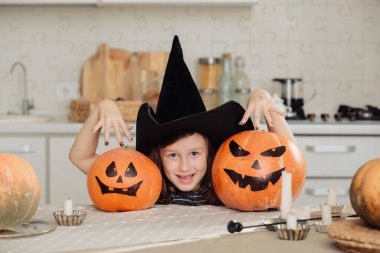 Cadılar bayramın kutlu olsun. Cadı kostümü içinde balkabağı oyan şirin bir kız. Mutlu aile Cadılar Bayramı için hazırlanıyor