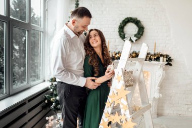 Genç ve güzel bir çift Noel 'i evde kutlarken ve birlikte Noel ağacı süslerken eğleniyorlar. Yılbaşı ve yeni yıl evde. Genç aile birlikte..