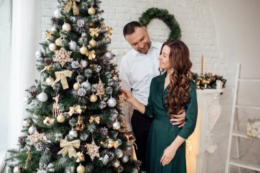 Noel 'i birlikte kutluyoruz. Noel ağacının yanında sarılan genç bir çift. Yeni yıl, Sevgililer Günü, aşk, romantizm konsepti