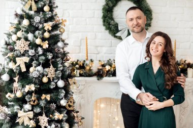 Noel 'i birlikte kutluyoruz. Noel ağacının yanında sarılan genç bir çift. Yeni yıl, Sevgililer Günü, aşk, romantizm konsepti