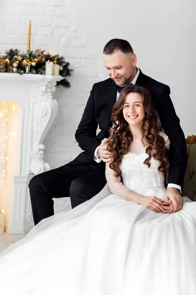 クリスマスの結婚式の日にクリスマスツリーで飾られた背景にスタジオでポーズをとっている愛の花嫁と新郎の若いカップル 幸せと愛の瞬間をお楽しみください — ストック写真