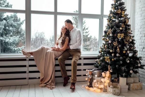 Couple Love Festive Clothers Sitting Hugging Large Window Christmas Tree — Stock Photo, Image