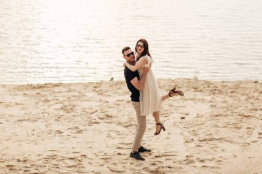 Deniz altyapısında erkek arkadaşıyla kucaklaşan çekici genç bir kadın. Açık havada göl kenarında duran mutlu bir çiftin fotoğrafı..