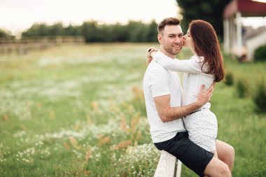 Güzel genç bir çift sıcak bir yaz gününde parkta sarılıp eğleniyor..