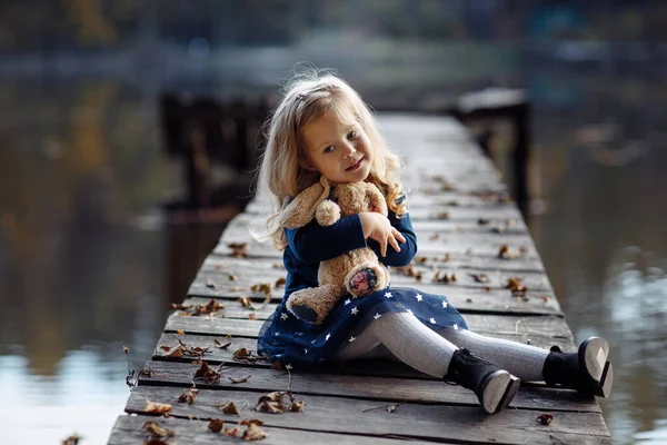 Egy Gyönyörű Kislány Kezében Egy Játékkal Őszi Parkban Víz Mellett — Stock Fotó