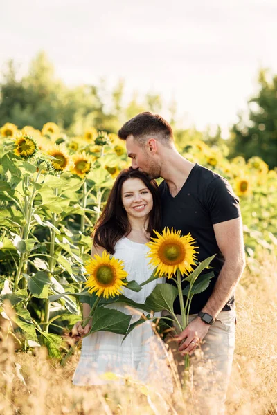 美丽的一对夫妇在向日葵地里玩得很开心 恋爱中的男人和女人在开向日葵的田野里散步 男人拥抱女人 选择性重点 — 图库照片