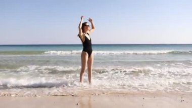 Sahilde, deniz kenarında mayo giymiş güzel bir kız. Siyah bir banyoda bronzlaşmış bir kız. Deniz havası.