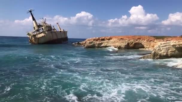 Las olas del mar golpearon contra el barco mercante abandonado en Chipre. Vista del mar cristalino, rocas en capas y hermosa naturaleza y barco. Azul a orillas del mar. enfoque selectivo — Vídeos de Stock